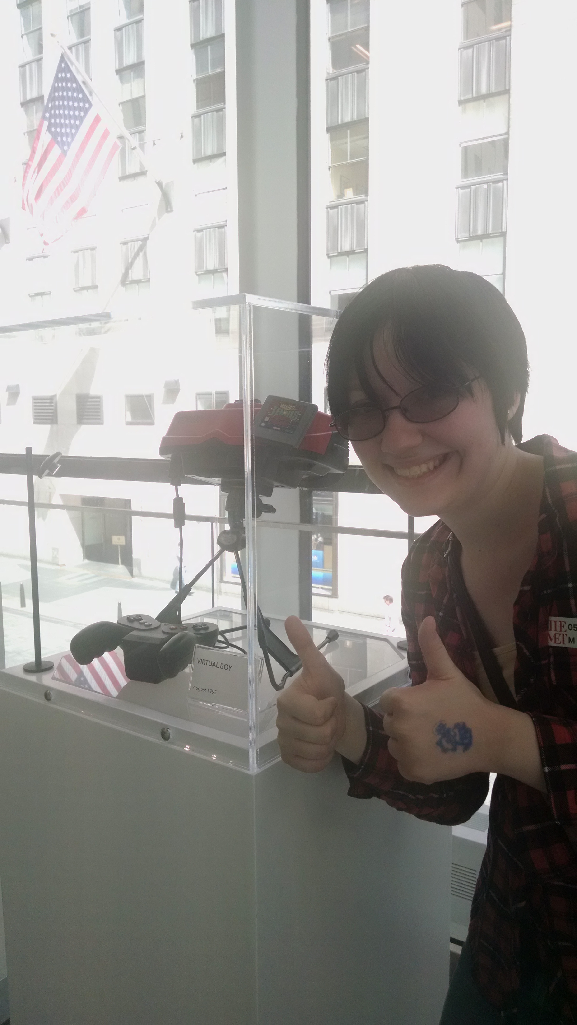 Rebecca Bilbrey poses smiling next to a Virtual Boy in New York City
